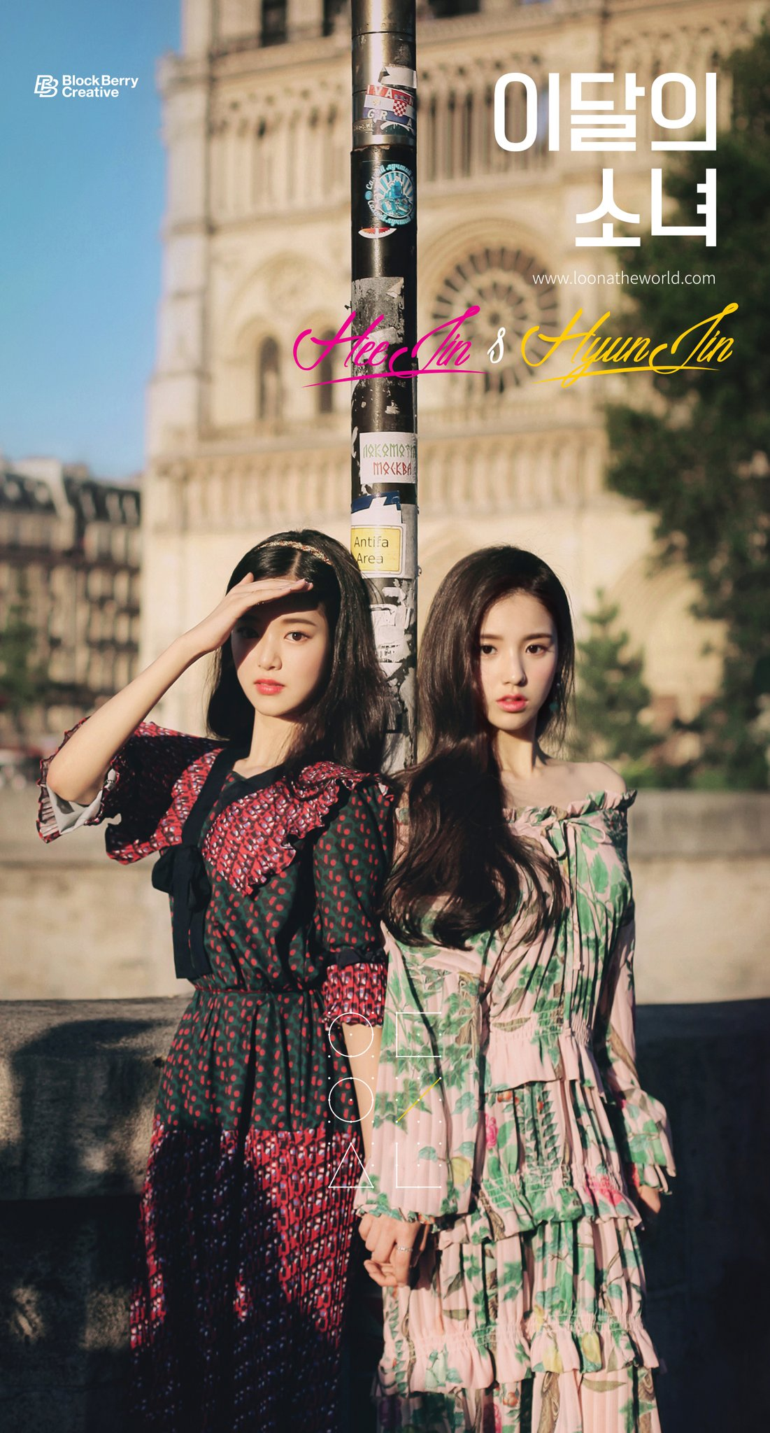 Hyunjin and Heejin standing in front of a pole.